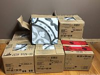 Eight boxes of porcelain tiles stacked on the floor with one tile taken out to show the design. Box labels show 20x20 cm and the brand CINCA visible, but seller notes Mona Serra Braga Porto tiles.