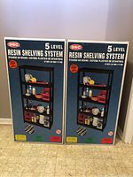 Photo of two boxed new GSC 5-level resin shelving systems showing the front of the packaging with shelving system image and branding.