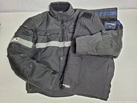 Snowmobile jacket and pants folded together on white background, showing jacket front and folded pants.