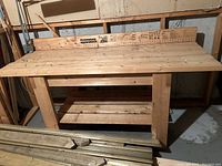 Front view of entire wooden workbench showing top, legs and lower shelf