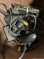 Photo showing two black Atari paddle controllers with yellow accents and cables tangled together in a box.