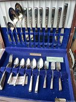 Full view of the Community branded silverplate flatware set neatly arranged in original blue velvet storage case covering knives, forks, spoons, and serving utensils.
