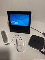 Lot view showing Amazon Echo Show 8, Apple TV, Vivitar plug-in speaker, and small gray speaker with 3.5mm audio cable