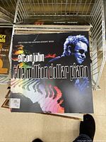 Photo showing cover of Elton John The Million Dollar Piano tour book with colorful piano image and text.
