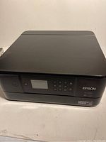 Front angled photo showing the Epson XP-6000 printer with control panel, LCD display, and buttons on front.