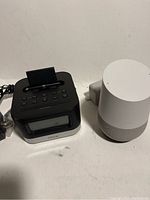 Photo showing Google Home smart speaker and iHome iPhone dock radio side by side on a surface.