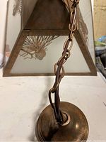 Close-up of the chain and rustic bronze finish on the top metal mounting plate of the hanging light fixture.