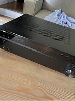 Black Insignia stereo receiver showing top ventilation and front panel with control buttons and volume knob