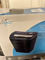 Photo of the damaged cardboard box packaging showing the Omnitech paper shredder and main features.