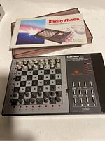 Photo showing the Radio Shack 1650 Electronic Chess Game with box and manual in background.