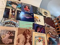 Photo displaying a collection of vinyl LP album covers arranged on a surface showing various rock artists including Neil Diamond, The Marshall Tucker Band, Carly Simon, and Christopher Cross.