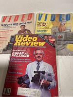 Three vintage video magazines arranged overlapping each other showing some cover details like titles and images related to 1980s video technology.