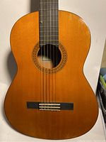 Full front view of Yamaha classical guitar showing natural wood body and strings.
