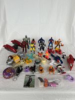 Front view of assortment including action figures, toy vehicles, and various accessories laid out on white background