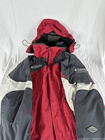 Front view of a red and gray Columbia Omni-Tech winter jacket with attached hood, displayed flat.