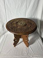 Full view of the dark wooden round plant stand with carved legs on a white backdrop.