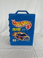 Closed view of blue plastic Hot Wheels 48 car carry case with vintage racing graphics and handle
