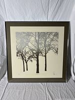 Full view of limited edition framed artwork showing black silhouetted trees on white background with silver frame and brown/dark green mat.