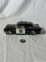 Side profile of the black and white 1955 Buick Century police car model with '2150' marked on roof and side, showing detailed wheels and paint.
