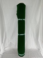 Full view of the puzzle mat rolled up vertically showing its length and green felt material.