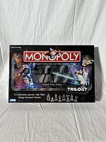 Front view of the Star Wars Monopoly board game box showing the title and original trilogy branding with images of main characters and collectible tokens.