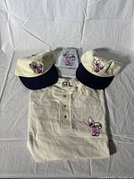 Two vintage Energizer Bunny hats, one vintage polo shirt with Energizer Bunny embroidery laid out on white background