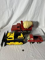 Three vintage Tonka pressed steel toy trucks under natural light showing condition and scale with a quarter for size reference.