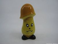 Front view of vintage angry mushroom-shaped ceramic shaker showing facial expression and colors.