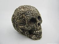 Angled view of the vintage Day of the Dead skull showing detailed floral and vine carvings.