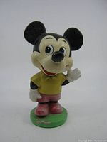 Front view of the Disney Mickey Mouse bobblehead doll with green base, showing wear and paint condition.