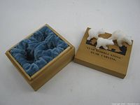 Three white star marble stone carved bears next to wooden box with lid showing black silhouette and text