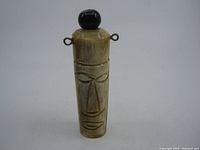 Front view of hand-carved Tiki god vial pendant showing detailed facial features and stopper cap.