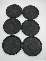 Six black carved indigenous native design drink coasters placed on white background showing front side with carved motif detail.