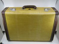 Front view of the yellow Old McBrine suitcase with brown leather corner trim and handle, showing the full exterior and latches.