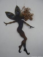 Front view of metal fairy ornament showing curled copper hair and decorated wings, hanging by wire loop.