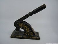 Photo showing side view of the Victorian cast iron embossing stamp with floral painted pattern and wooden handle.
