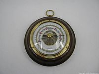 Front view of the circular wooden framed Rensie barometer with brass bezel and visible internal mechanism.