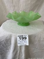 Side view of the jadeite green wavy edge fruit bowl showing the pedestal base and ruffled rim.