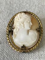 Front view of silver gilt shell cameo pendant showing carved female profile with twisted rope frame. Missing left side piece of the frame is visible.