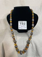 Front view of the vintage sterling silver and amber necklace displayed on a stand with a lot number card showing weight and length.