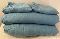 Folded blue linen bedding set showing all pieces stacked neatly.