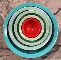 Top view of all five nesting Cali plastic bowls stacked inside each other by size and color.