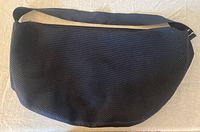 Front view of navy mesh shoulder bag laid flat showing semicircular design and mesh texture.