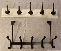 Wooden back mounted rack with five dark metal hooks and one horizontal rail rack with five double rounded prong hooks in dark metal
