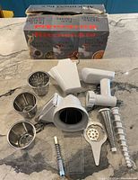 Photo of all attachments and components arranged on a countertop with original box in background.