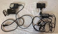 Photo showing both Nikon Coolpix digital cameras, battery packs, and power cables laid out together on a surface.