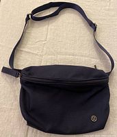 Front view of navy blue Lululemon belt bag, showing zip closure and logo.