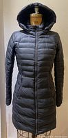 Front view of black Lululemon down coat on dress form showing full zipper and hood.