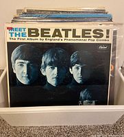 Photo of the front album cover of 'Meet The Beatles!' by The Beatles, showing four band members in black and white with a prominent title header.