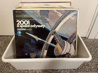 Plastic bin containing vinyl LP records with visible cover art for 2001: A Space Odyssey soundtrack on forefront.